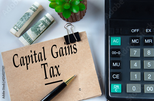 CAPITAL GAINS TAX - words on a brown sheet on the background of a calculator and banknotes photo