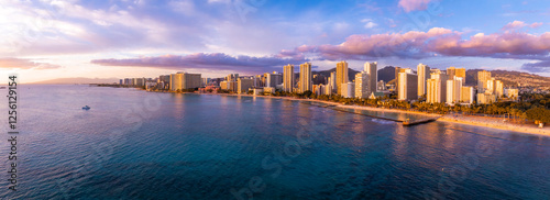 Aerial view of Waikiki Beach in Honolulu, Oahu, Hawaii, at sunset. High rise hotels line the shore, with mountains and colorful skies in the background. photo