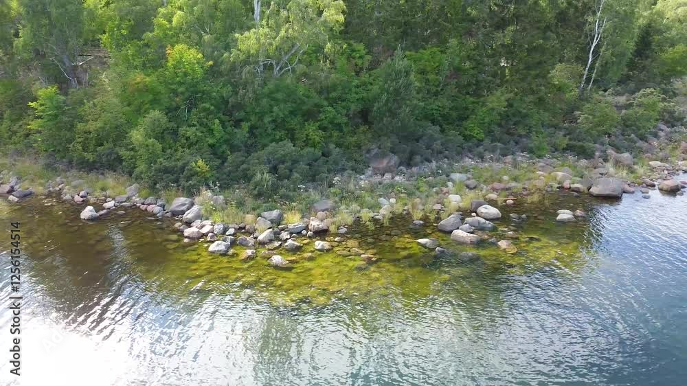 Drone flying above water's body surrounded by a lush forest on a sunny day in Sweden, Gavle Drone flying above water's body surrounded by a lush forest on a sunny day in Sweden, Gavle