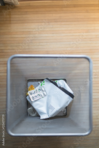 View from above of waste in a trash bin on wooden floor