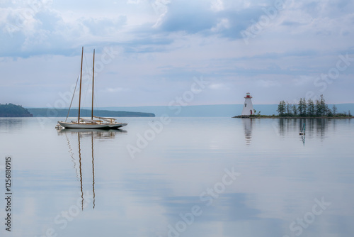 Two moored sailboats and Kidston Island Lighthouse in Baddeck, Nova Scotia, Canada