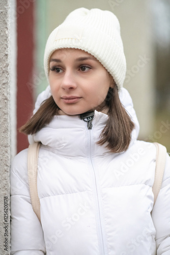 Portrait of a young beautiful dark-haired girl in light clothes on the street in early spring.