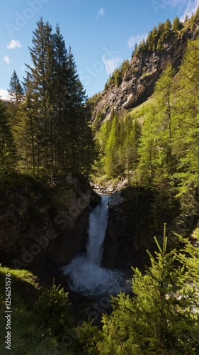 Vertical shot ofscenic waterfall in Swiss Alps. Perfect for lifestyle, travel, vacation, and adventure in the Swiss Alps photo