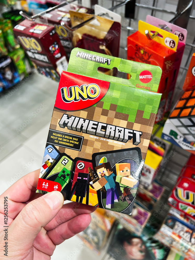 Naklejka premium Kyiv, Ukraine - February 09, 2025: Hand holding a Minecraft themed Uno card pack displayed in a store