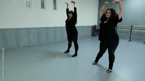 Two fat women dancing in a gray dance hall. Women dancing erotically. Beautiful fat women