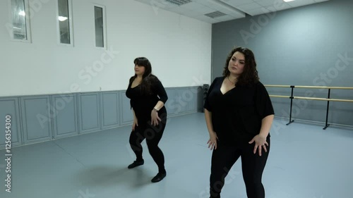 Two fat women dancing in a dance hall. Women in black clothes