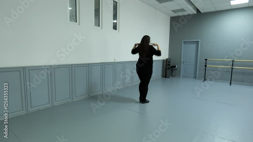 Young fat woman in black clothes dancing in the dance hall. Beautiful fat woman doing erotic movements. Brunette woman dancing