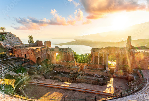 Panoramic view of a beautiful sunset in Ancient Theatre of Taormina in Sicily with antique italian town and mountain sunset on background. Holidays and sightseeing in Italy