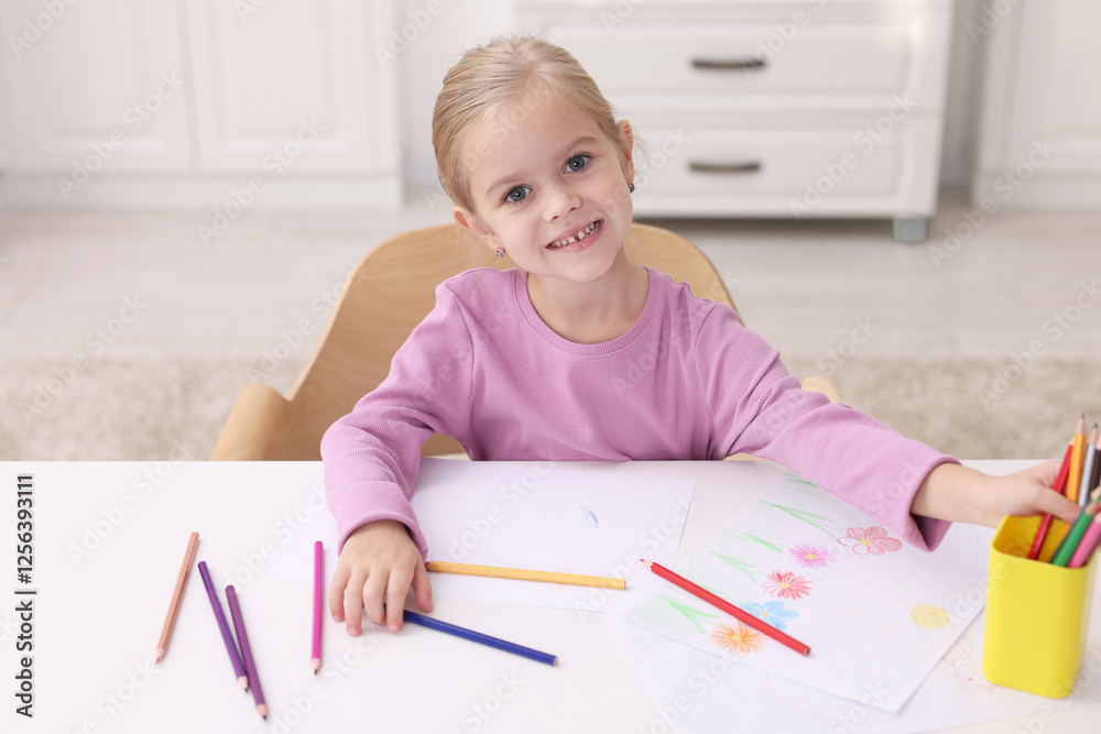 Smiling girl at white table with drawing in kindergarten Smiling girl at white table with drawing in kindergarten