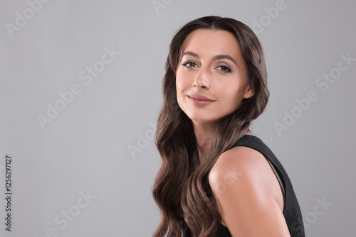 Hair styling. Portrait of beautiful woman with wavy long hair on grey background. Space for text