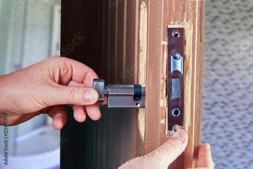 Door lock installer setting up mortice deadlock in home.