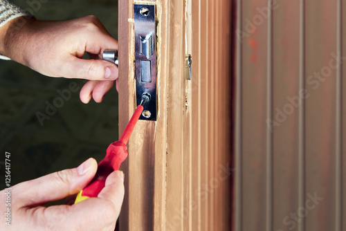 Joiner carefully fitting sash lock into wooden door edge. photo