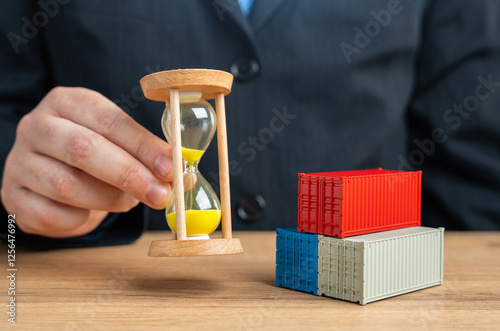 Obraz na płótnie Businessman holding hourglass near sea shipping containers
