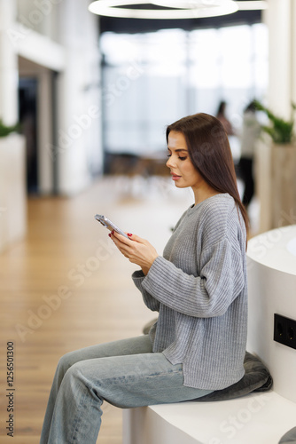 Small business entrepreneur looking at her phone and smiling while communicating with her office Free Download Small business entrepreneur looking at her phone and smiling while communicating with her office - GFXLoad
