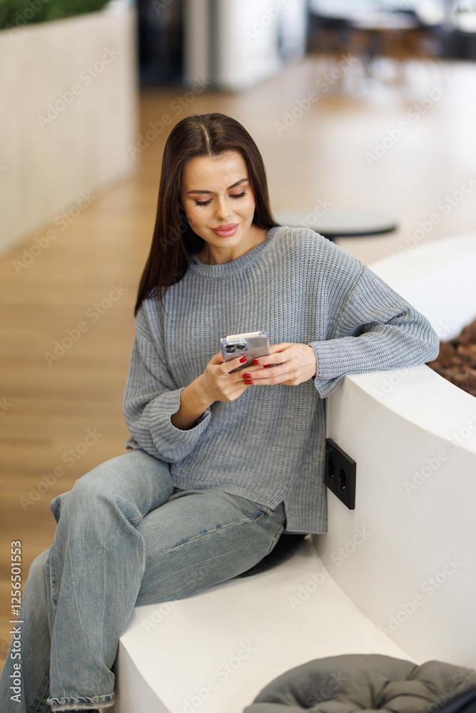 Obraz premium Young smiling business woman using phone in office