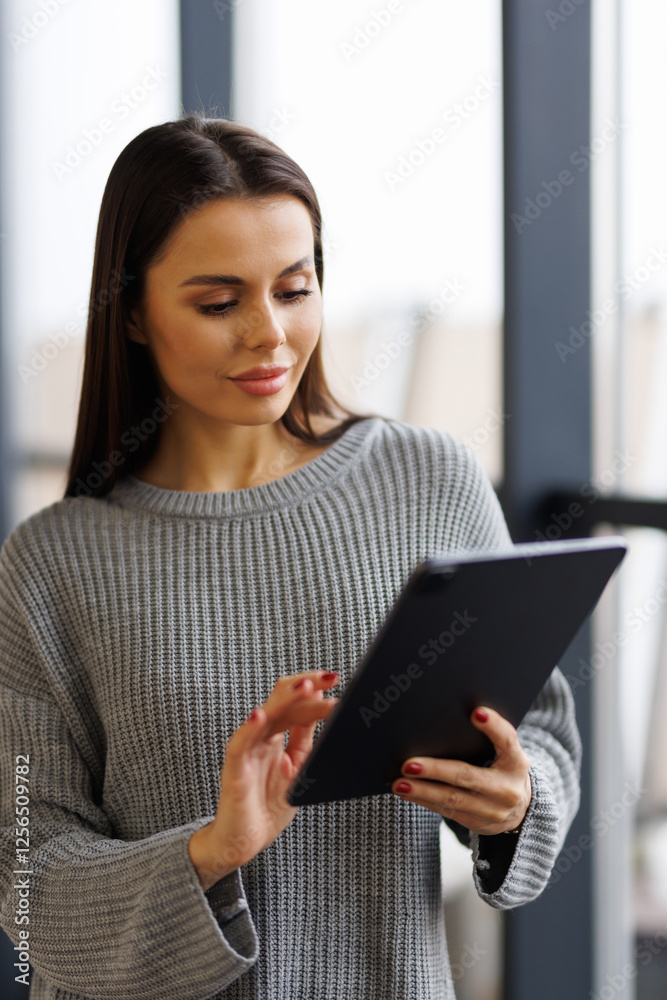 Young female manager working on digital tablet while standing in modern office Young female manager working on digital tablet while standing in modern office