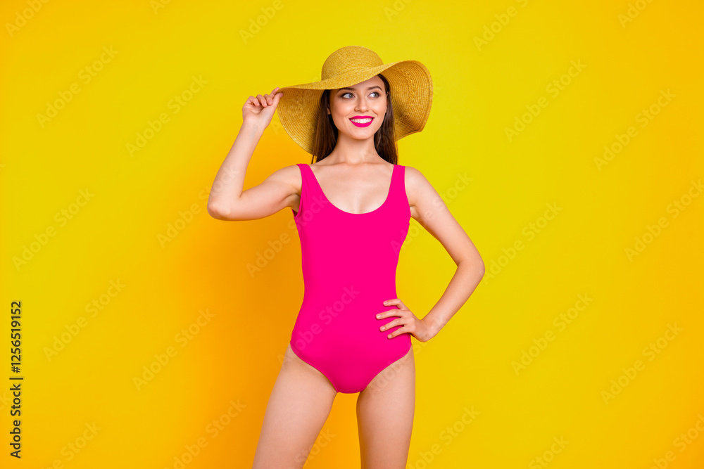 Beach style Close up portrait of girl with bright red lipstick looks to the side holding her hat with one hand and smile isolated on yellow background Beach style Close up portrait of girl with bright red lipstick looks to the side holding her hat with one hand and smile isolated on yellow background