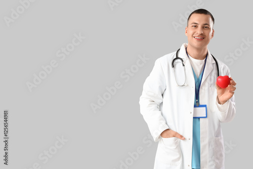 Handsome doctor with heart on light background