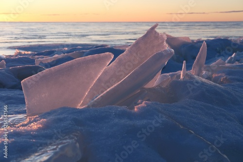 Fototapeta Naklejka Na Ścianę i Meble -  Shattered ice formations on a frozen shoreline at sunset. Sharp ice floes frozen into coastline of Baltic sea in winter.