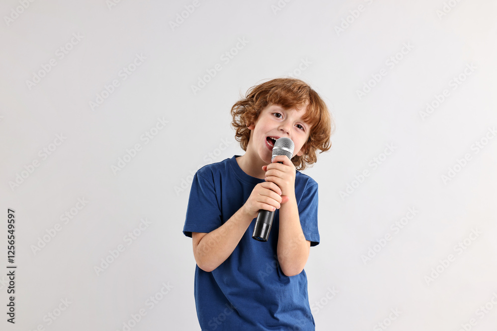 Little boy with microphone singing on light grey background Little boy with microphone singing on light grey background
