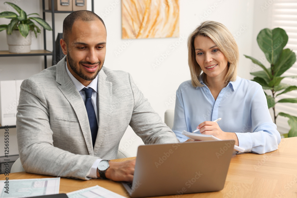 Coworkers with laptop working together in office