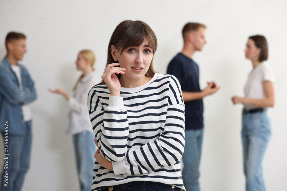 Fototapeta premium Young woman feeling uncomfortable among people indoors, selective focus