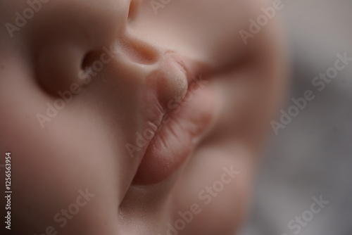 A hyper-realistic close-up of a doll's face, showcasing lifelike skin texture and soft lips. The fine details and gentle lighting create an illusion of realism, making it almost indistinguishable from