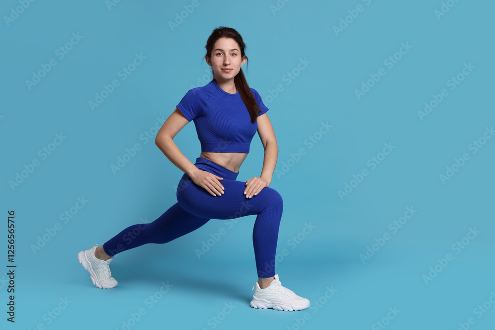 Woman in sportswear exercising on light blue background, space for text Woman in sportswear exercising on light blue background, space for text