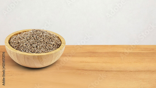 A wooden bowl filled with whole cumin seeds, known as 