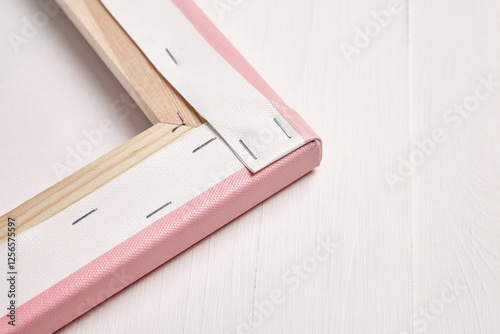 Close-up view of the backside of a pink photo canvas print, showing the neatly folded corners, tight stretching, and stapled gallery wrap on a wooden frame