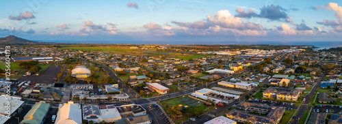 Aerial image of a town on Kauai island, Hawaii, featuring a grid like street layout, a dome shaped building, lush greenery, and the ocean in the distance. photo