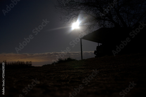 night image of a farm, in which you can see the moon, and the luminosity of the city reflected in the sky