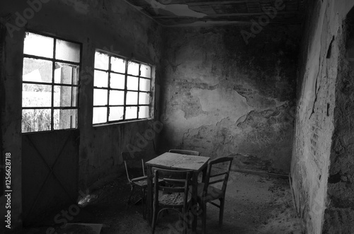 black and white photograph of the dining room of an abandoned rural house