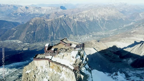 Breathtaking view from the highest point of Aiguille du Midi with the glass skywalk, overlooking the lower cable car station, Chamonix valley, and the stunning peaks of the French Alps.