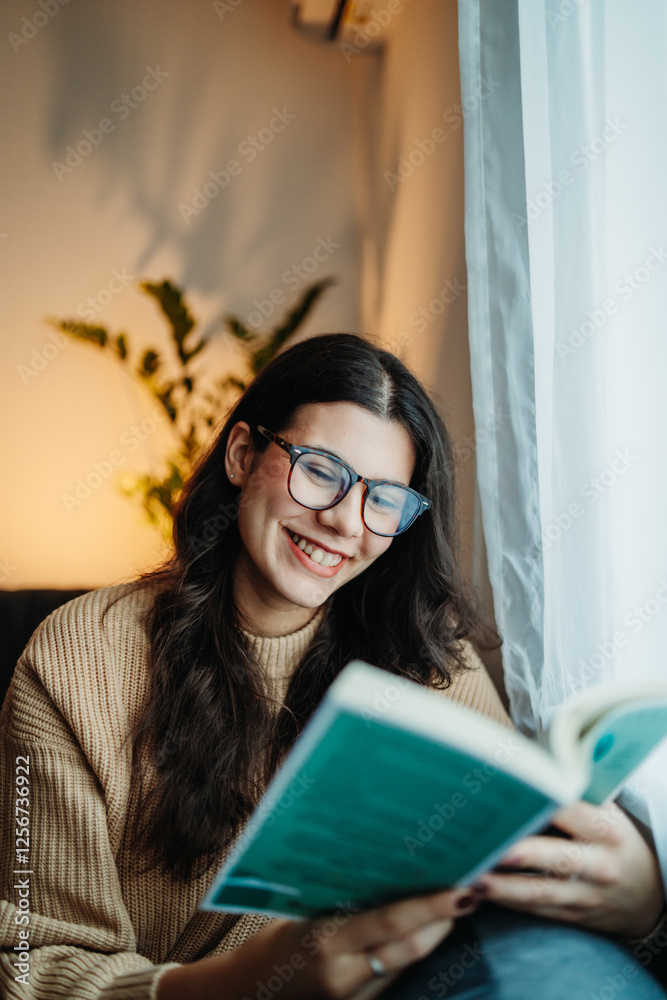Young caucasian woman reading book or learning by the window Young caucasian woman reading book or learning by the window