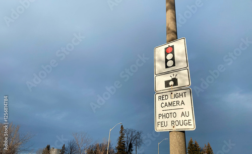Red Light Camera Traffic Sign with Bilingual Text on a Street Pole
