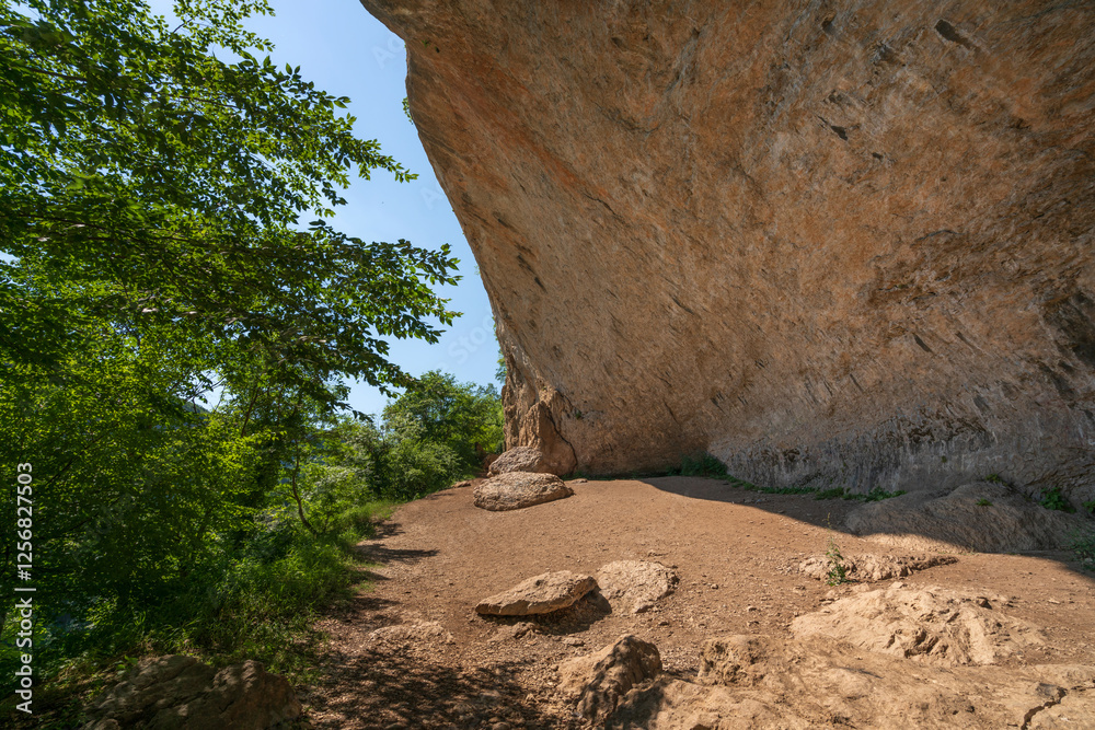 Obraz premium View of the steep sandy shore above the Belaya River on a sunny summer day, Kamennomostsky village, Republic of Adygea, Russia