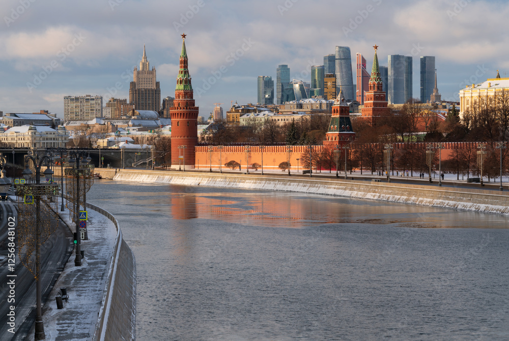 Obraz premium Vodovzvodnaya, Blagoveshchenskaya and Borovitskaya towers on the Kremlin embankment of the Moskva River and the Moscow City Business Center in the background on a sunny winter day, Moscow, Russia