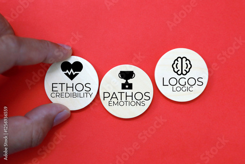 wooden circle with icons and the words Credibility Emotions and Logic ethos pathos and logos photo