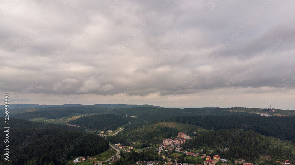 Fototapeta premium Magnificent Aerial View Of Mountains And Dense Forests Under Dark Clouds, With Raindrops Falling, Creating A Dramatic And Serene Atmosphere In A Remote Natural Landscape. 
