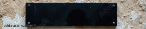 Blank black glass signplate against aged stone , stone wall, facade, textured photo