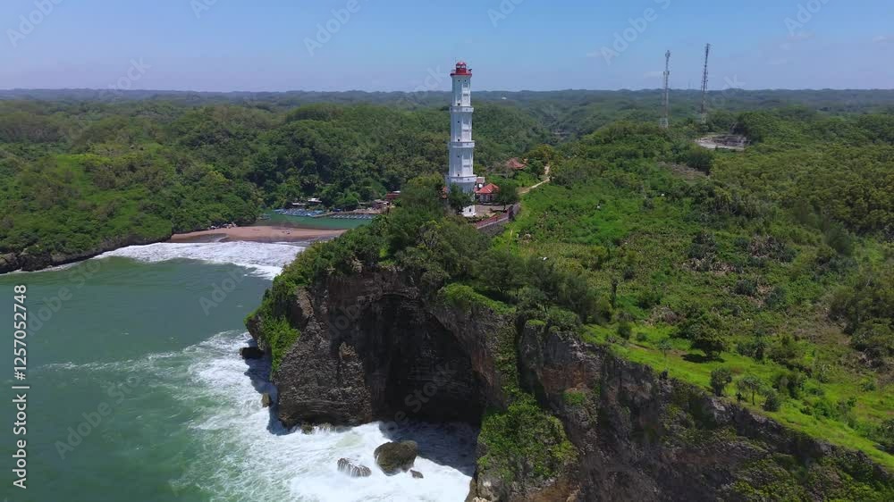 Aerial drone view Lighthouse or mercusuar on a coral hill on Baron beach, Gunung Kidul, Yogyakarta, which is also a tourist destination and traditional fishing port Aerial drone view Lighthouse or mercusuar on a coral hill on Baron beach, Gunung Kidul, Yogyakarta, which is also a tourist destination and traditional fishing port