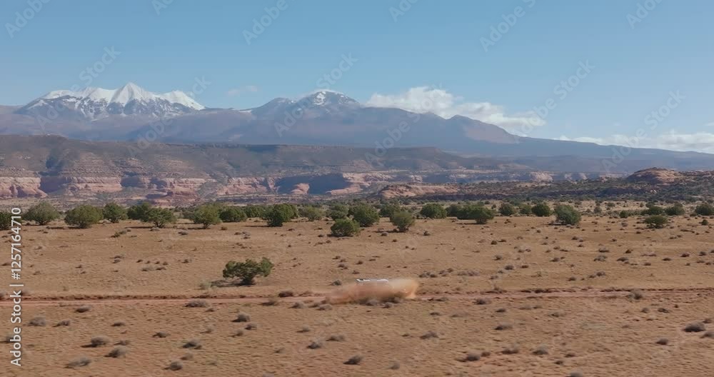 Truck hits puddle, sprays water on dirt road in desert with mountains in background Truck hits puddle, sprays water on dirt road in desert with mountains in background