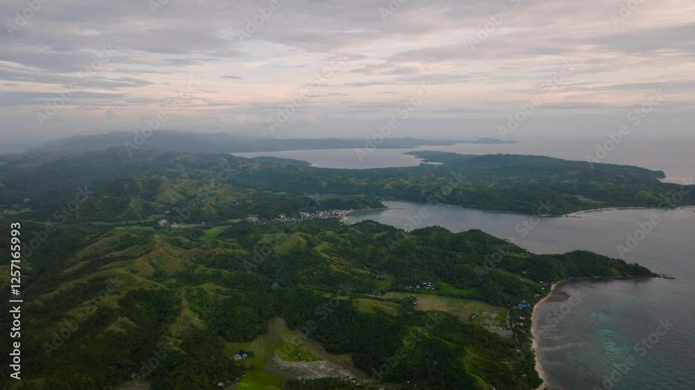 Expansive view of rolling hills, bays, and villages surrounded by greenery and calm waters under a cloudy sky. Romblon, Philippines. Expansive view of rolling hills, bays, and villages surrounded by greenery and calm waters under a cloudy sky. Romblon, Philippines.