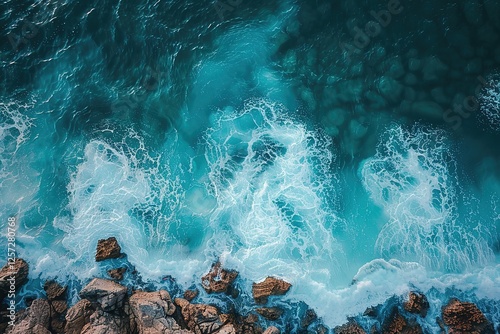 an aerial view of the ocean with rocks and waves crashing on the shore.