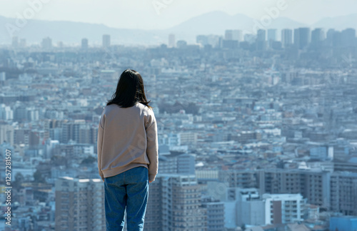 人生に疲れて思いつめた若い女性が高層階から街を眺めている