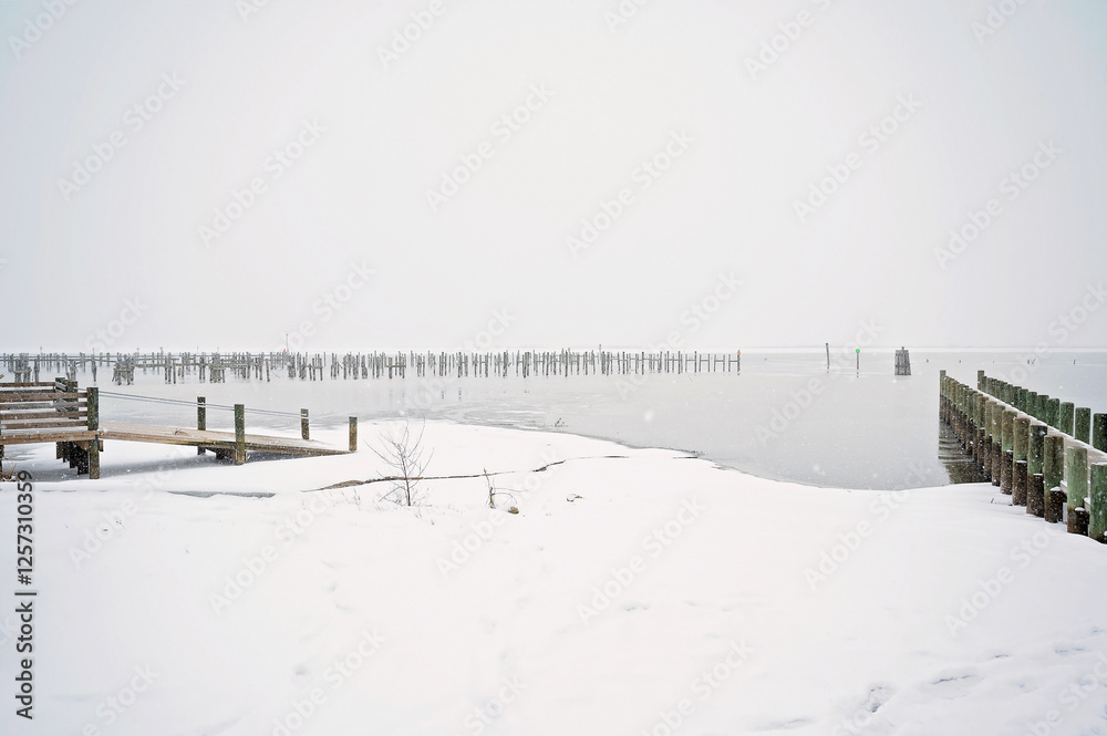 Snow-covered dock and frozen waterfront in a peaceful winter scene Snow-covered dock and frozen waterfront in a peaceful winter scene