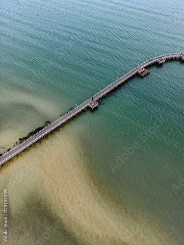 Aerial view of wooden pier over green sea.
