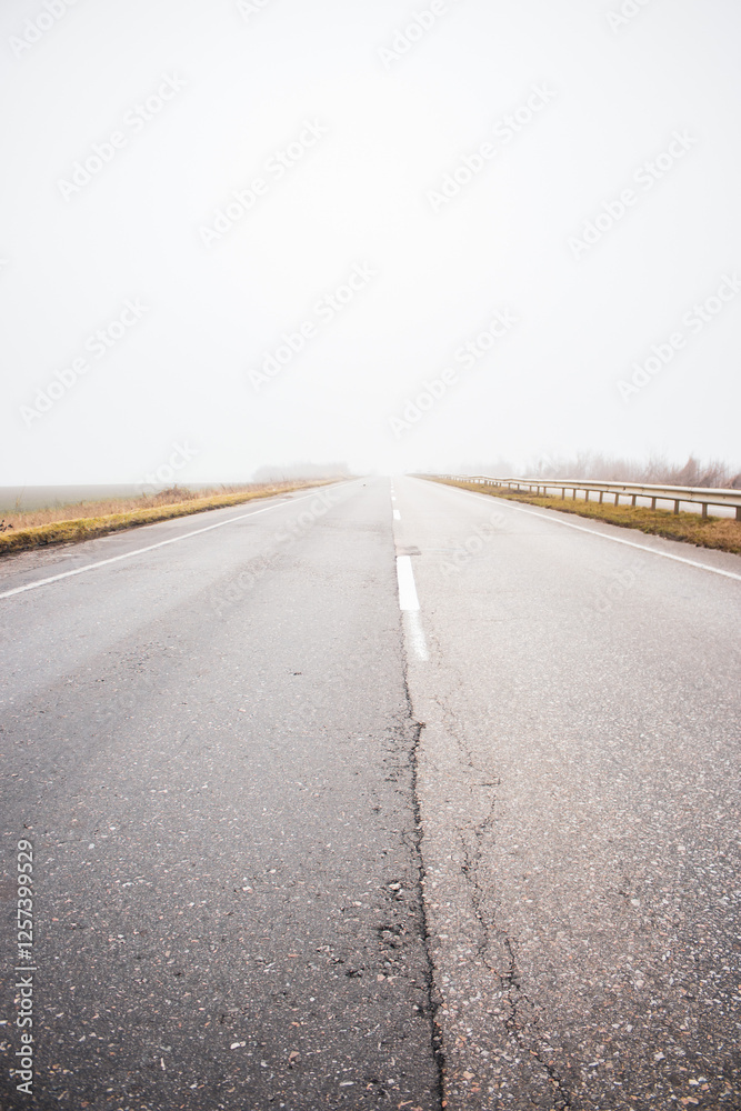 Empty highway in the fog. Bad weather on the road. Road on foggy day in perspective with copy space.