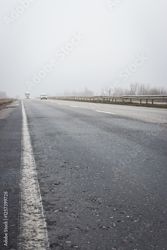 Obraz na płótnie Cars on highway in the fog. Bad weather on the road. Road on foggy day in perspective with copy space. Driving conditions concept. Ghostly misty road. Caution and danger on the road. w salonie